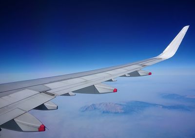 Cropped image of airplane wing against a sunny, bright sky