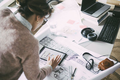 Aerial view of female architect in office at home looking at tablet