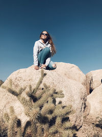 Low angle view of woman on rock against sky