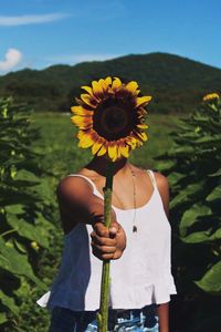 Rear view of woman holding flower in field