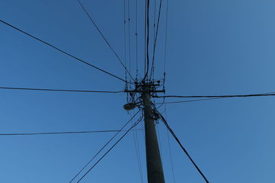 Low angle view of electricity pylon against blue sky