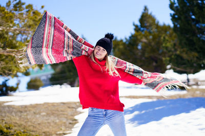 Portrait of smiling young woman standing on snow covered field