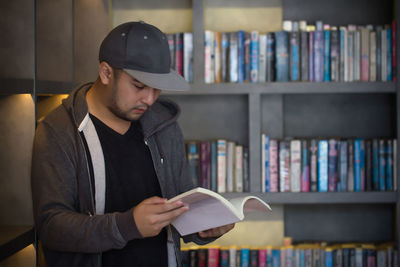 Young man reading book in library