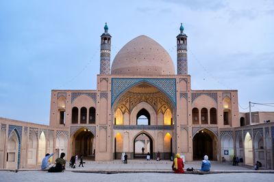 People in front of historic building against sky