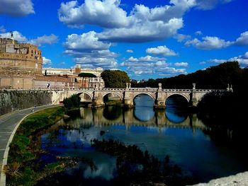Bridge over river against cloudy sky