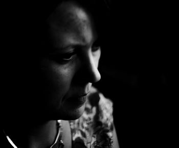 Close-up of serious mature woman against black background