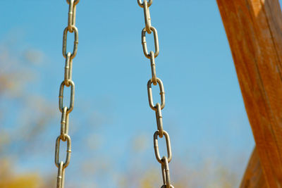 Low angle view of chain hanging against sky