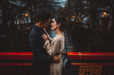 Young couple standing on bridge at night