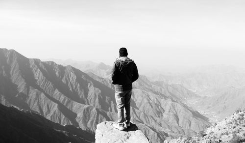Rear view of man standing on snowcapped mountain