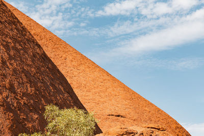 Low angle view of uluru against cloudy sky