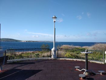 Street light by sea against blue sky