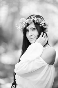 Portrait of young woman standing against trees