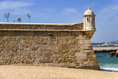 Cropped stone wall against blue sky