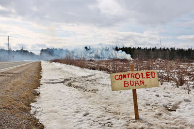 Controlled burn sign  with active burn in background on a farm property to create more arable land