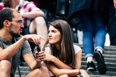 Young couple looking up while sitting outdoors