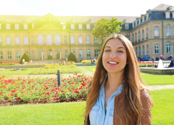 Smiling cheerful young woman in front of neues schloss of stuttgart, germany.