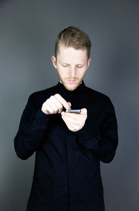 Young man standing against gray background