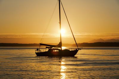 Silhouette boat sailing on sea during sunset