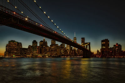 Illuminated suspension bridge over river at night