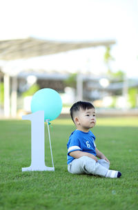 Cute baby boy sitting by number 1 at park