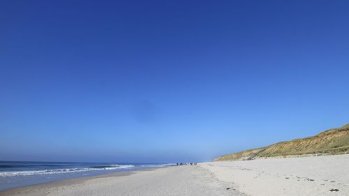 Scenic view of beach against clear blue sky