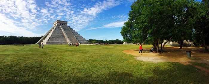 People on field in park against cloudy sky