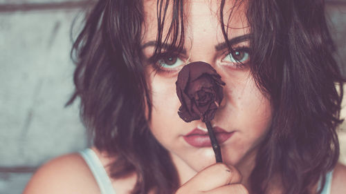 Close-up portrait of young woman holding dry rose