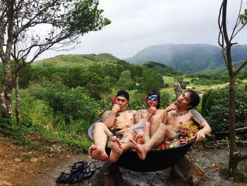 People sitting on land against trees