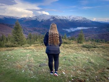 Rear view of woman standing on mountain against sky