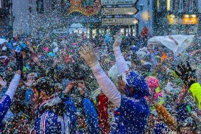 Crowd throwing colorful confetti in city during celebration