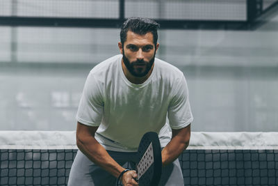 Beautiful man playing padel tennis, racket in hand concentrated. young sporty boy ready for match