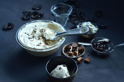 High angle view of ice cream in bowls with peanut butter cupcakes and chocolates on table