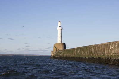 Low angle view of lighthouse by sea against clear sky