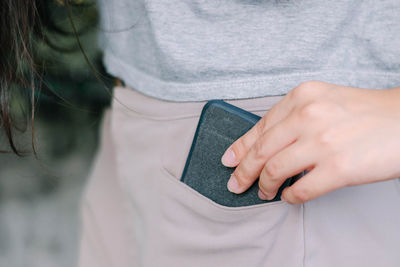 Midsection of woman holding mobile phone in pocket