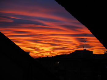 Low angle view of silhouette city against orange sky