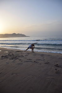 Man on beach against sky during sunset