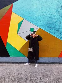 Full length of woman standing against graffiti wall