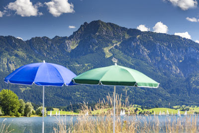 Parasols by forggensee lake against tegelberg mountain