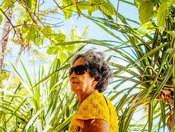 Portrait of woman wearing sunglasses standing against plants