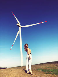 Wind turbines on field against sky