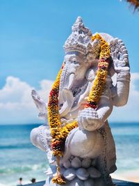 Statue by sea against sky