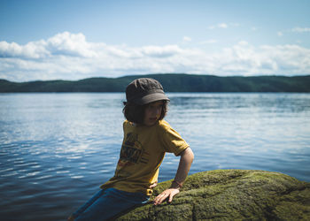 Boy on lake against sky