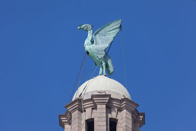 Low angle view of statue against clear blue sky