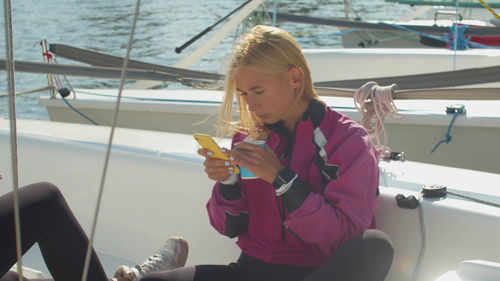 Woman using mobile phone while sitting on boat