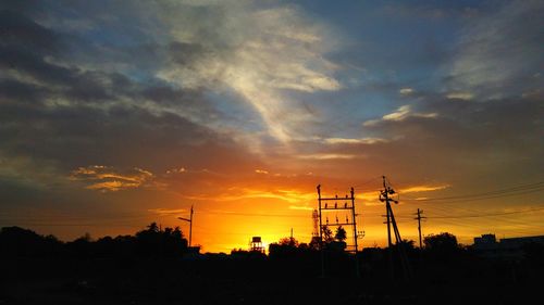 Low angle view of silhouette electricity pylon against sky during sunset