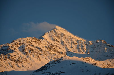 Snow covered rocky mountain against sky