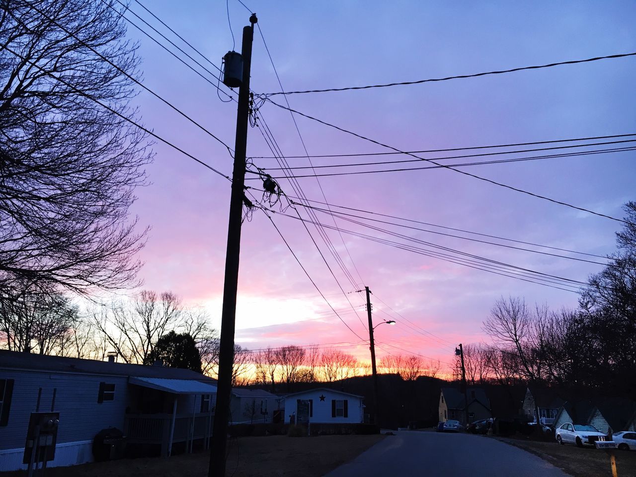 power line, electricity pylon, cable, transportation, sky, sunset, electricity, power supply, building exterior, silhouette, tree, built structure, power cable, connection, street light, architecture, road, car, street, low angle view