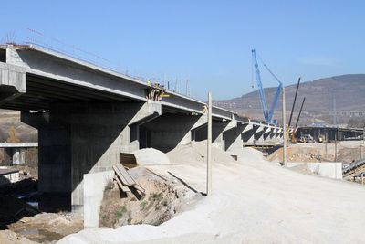 Construction site by bridge against clear sky