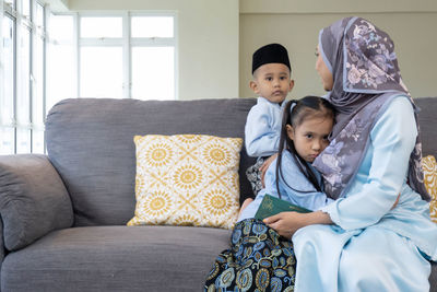 Cute boy sitting on sofa at home