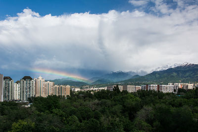 The rainbow and buildings against white beautiful clouds and snow mountains 